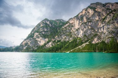 Braies gölü, İtalya 'nın bulutlu bir gününde çam ormanları ve Dolomitlerin kayalık dağlarıyla çevrilidir. Yüksek kalite fotoğraf
