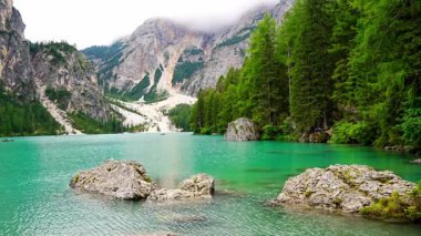 Braies gölü, İtalya 'nın bulutlu bir gününde çam ormanları ve Dolomitlerin kayalık dağlarıyla çevrilidir. Yüksek kalite 4k görüntü