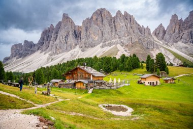 Puez Odle Doğa Parkı 'ndaki Dolomite manzarası. Alp yaylalarından ahşap evler ve yeşil çayırlar görünüyor. Yüksek kalite fotoğraf