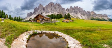 Puez Odle Doğa Parkı 'ndaki Dolomite manzarası. Alp yaylalarından ahşap evler ve yeşil çayırlar görünüyor. Yüksek kalite fotoğraf
