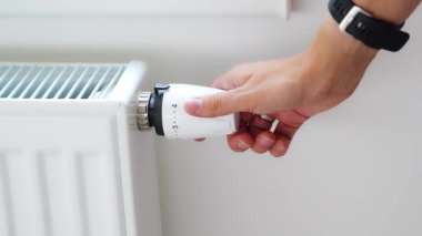 Bir kadının eli akü ısıtma düğmesini çevirir. Evde, bir dairede ısıtma. Isıtma fiyatları. Yüksek kalite 4k görüntü