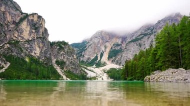 Braies gölü, İtalya 'nın bulutlu bir gününde çam ormanları ve Dolomitlerin kayalık dağlarıyla çevrilidir. Yüksek kalite 4k görüntü