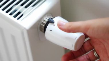 Bir kadının eli akü ısıtma düğmesini çevirir. Evde, bir dairede ısıtma. Isıtma fiyatları. Yüksek kalite 4k görüntü