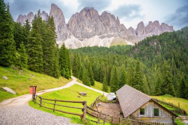 Puez Odle Doğa Parkı 'ndaki Dolomite manzarası. Alp yaylalarından ahşap evler ve yeşil çayırlar görünüyor. Yüksek kalite fotoğraf