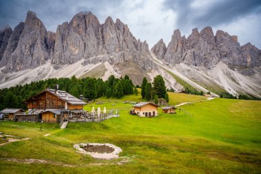 Puez Odle Doğa Parkı 'ndaki Dolomite manzarası. Alp yaylalarından ahşap evler ve yeşil çayırlar görünüyor. Yüksek kalite fotoğraf