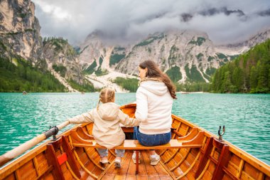 İtalya 'nın bulutlu bir gününde kızıyla birlikte Lago di Braies gölünde büyük kahverengi bir teknede oturan bir kadın. Avrupa 'da aile tatili. Yüksek kalite fotoğraf