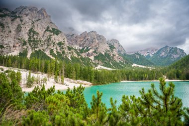 Braies gölü, İtalya 'nın bulutlu bir gününde çam ormanları ve Dolomitlerin kayalık dağlarıyla çevrilidir. Yüksek kalite fotoğraf