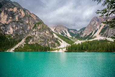 Braies gölü, İtalya 'nın bulutlu bir gününde çam ormanları ve Dolomitlerin kayalık dağlarıyla çevrilidir. Yüksek kalite fotoğraf