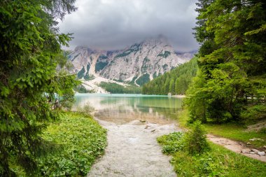 Braies gölü, İtalya 'nın bulutlu bir gününde çam ormanları ve Dolomitlerin kayalık dağlarıyla çevrilidir. Yüksek kalite fotoğraf