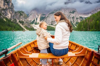 İtalya 'nın bulutlu bir gününde kızıyla birlikte Lago di Braies gölünde büyük kahverengi bir teknede oturan bir kadın. Avrupa 'da aile tatili. Yüksek kalite fotoğraf