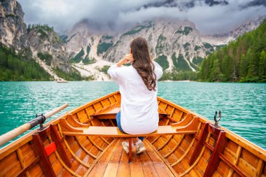 İtalya 'nın bulutlu bir gününde Lago di Braies gölünde büyük kahverengi bir teknede oturan bir kadın. Avrupa 'da yaz tatili. Yüksek kalite fotoğraf