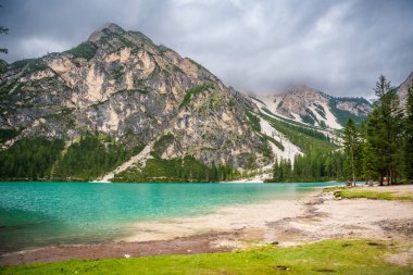 Braies gölü, İtalya 'nın bulutlu bir gününde çam ormanları ve Dolomitlerin kayalık dağlarıyla çevrilidir. Yüksek kalite fotoğraf