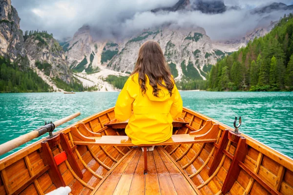 İtalya 'nın bulutlu bir gününde Lago di Braies gölünde büyük kahverengi bir teknede oturan bir kadın. Avrupa 'da yaz tatili. Yüksek kalite fotoğraf