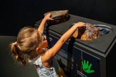 Prag, Çek Cumhuriyeti - 23 Ağustos 2023: Prag 'daki Dinozor Müzesi' nde fosile dokunan kız. Yüksek kalite fotoğraf