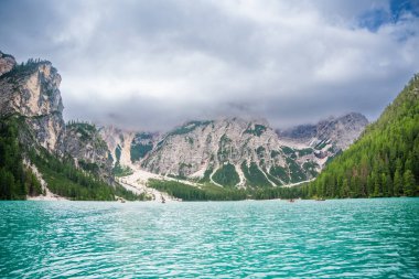 Braies gölü, İtalya 'nın bulutlu bir gününde çam ormanları ve Dolomitlerin kayalık dağlarıyla çevrilidir. Yüksek kalite fotoğraf