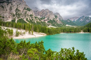 Braies gölü, İtalya 'nın bulutlu bir gününde çam ormanları ve Dolomitlerin kayalık dağlarıyla çevrilidir. Yüksek kalite fotoğraf
