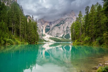 Braies gölü, İtalya 'nın bulutlu bir gününde çam ormanları ve Dolomitlerin kayalık dağlarıyla çevrilidir. Yüksek kalite fotoğraf