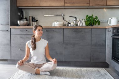 Genç mutlu kadın mutfakta kirli tabakların arkasında oturuyor. Yavaşla, kendine dikkat et, yavaş yaşam konsepti. Yüksek kalite fotoğraf