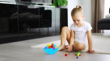 Oturma odasında yerde tahta dengeleyici oyuncakla oynayan küçük bir kız. Yüksek kalite 4k görüntü