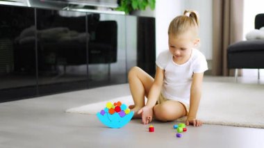Oturma odasında yerde tahta dengeleyici oyuncakla oynayan küçük bir kız. Yüksek kalite 4k görüntü