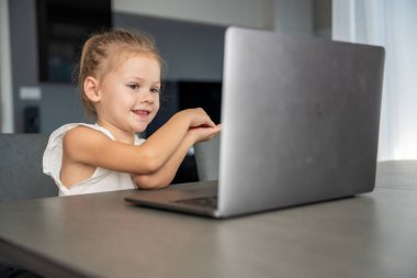 Küçük kız dizüstü bilgisayarında parmak jimnastiği yapıyor. Uzaktan öğrenme konsepti. Yüksek kalite fotoğraf