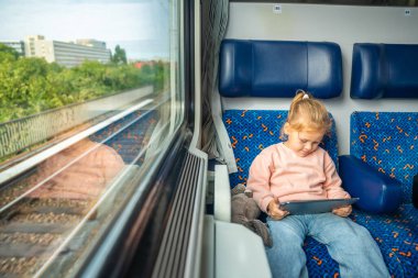 Güzel küçük kız Almanya, Avrupa 'da tren yolculuğu sırasında dijital tablet kullanıyor. Yüksek kalite fotoğraf