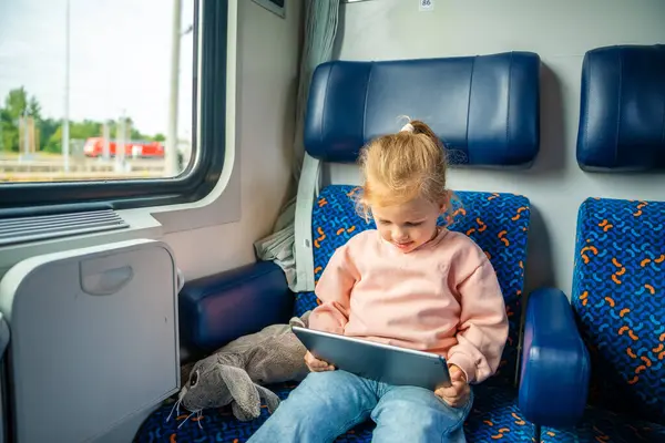 Little girl using digital tablet during traveling by railway, Europe. High quality photo