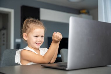 Küçük kız dizüstü bilgisayarında parmak jimnastiği yapıyor. Uzaktan öğrenme konsepti. Yüksek kalite fotoğraf