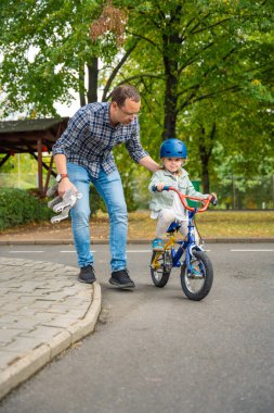 Genç bir baba, Çek Cumhuriyeti, Avrupa 'da Prag' da bir trafik parkında bisiklet sürmeyi çocuk kızına öğretiyor. Yüksek kalite fotoğraf