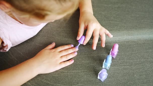 俯瞰小女孩在家里做指甲整形手术 用五彩缤纷的粉色 蓝色和紫色指甲油粉刷指甲 高质量的4K镜头 — 图库视频影像