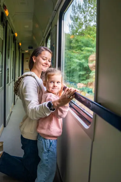 Family traveling in a train and looking through window. Woman with child traveling by railway, Europe. High quality photo
