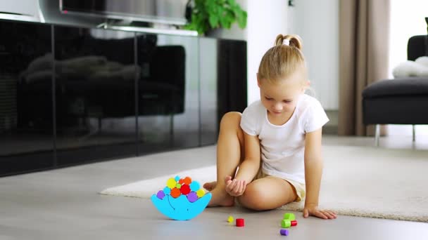 家のリビングルームの床に木製のバランスをとるおもちゃで遊ぶ小さな女の子 高品質の4K映像 — ストック動画