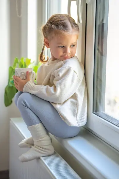 Petite Fille Pull Chaud Chaussettes Assises Regardant Par Fenêtre Tenant Photo De Stock