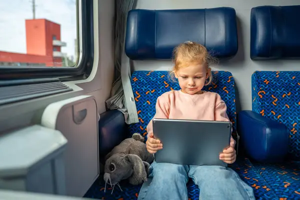 Little girl using digital tablet during traveling by railway in Germany, Europe. High quality photo