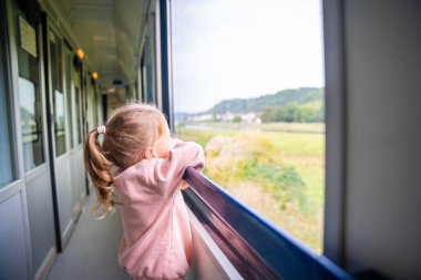 Güzel küçük kız dışarıdaki tren penceresinden dışarı bakıyor, yolculuk sırasında. Avrupa 'da demiryolu ile seyahat etmek. Yüksek kalite fotoğraf