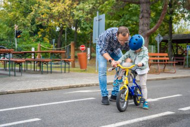 Genç baba, Çek Cumhuriyeti 'nin Prag kentindeki bir trafik parkında çocuk kızına bisiklet sürmeyi öğretiyor. Yüksek kalite fotoğraf