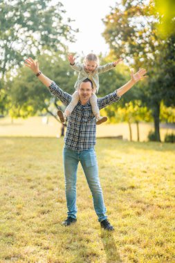 Genç baba ve küçük kızı Prag, Avrupa 'daki sonbahar parkında gün batımında birlikte eğleniyorlar. Yüksek kalite fotoğraf