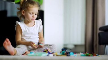 Yoğunlaşmış küçük kız evde oturma odasında yerde küçük inşaatçı oyuncağıyla oynuyor, eğitim oyunu, boş zaman aktiviteleri konsepti. Yüksek kalite fotoğraf