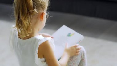 Küçük kız oturmuş peri masallarıyla dolu bir kitap okuyor. Yüksek kalite 4k görüntü