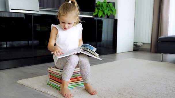 Симпатична Маленька Дівчинка Сидить Стосі Дитячих Книг Проливається Через Книгу — стокове відео
