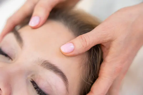 Close up view of healer hands performing by lightly touched access bars therapy on young woman head stimulating positive change thoughts and emotions in salon. Alternative medicine. High quality photo