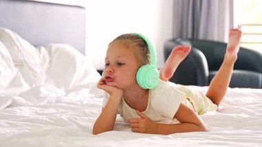 Küçük kız yatakta yatar, evde yeşil çocuk kulaklıklarıyla şarkı söyler ve dinlerdi. Yüksek kalite 4k görüntü