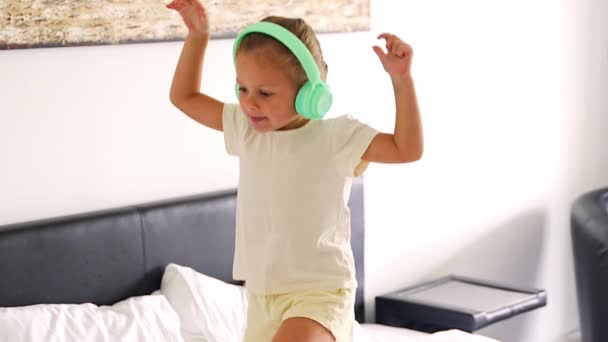 Menina Desfrutando Música Com Fones Ouvido Para Crianças Dançando Cama — Vídeo de Stock
