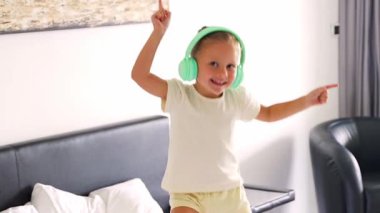 Little girl enjoying to the music with kids headphones and dancing at home in happy morning. High quality 4k footage