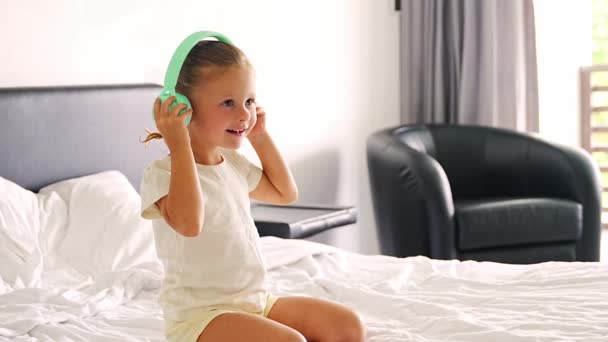 Little Girl Listening Music Using Green Kids Headphones Home Bed — Αρχείο Βίντεο