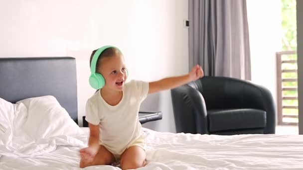 子供のヘッドフォンで音楽を聴き 幸せな朝に家で踊っているおかしい女の子 高品質の4K映像 — ストック動画