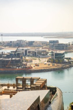 Abu Dabi, Birleşik Arap Emirlikleri - 4 Aralık 2023: Abu Dabi 'de denizin arka planında görülen adada inşaat vinçleriyle çevrili yeni binalar. Yüksek kalite fotoğraf