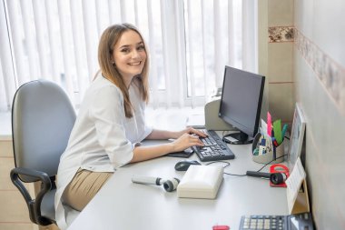 Dermatolog kadın üniformalı, eldivenli, doktorlu, bilgisayarlı, klinikteki muayene odasında çalışıyor. Genç bir uzman. Yüksek kalite fotoğraf