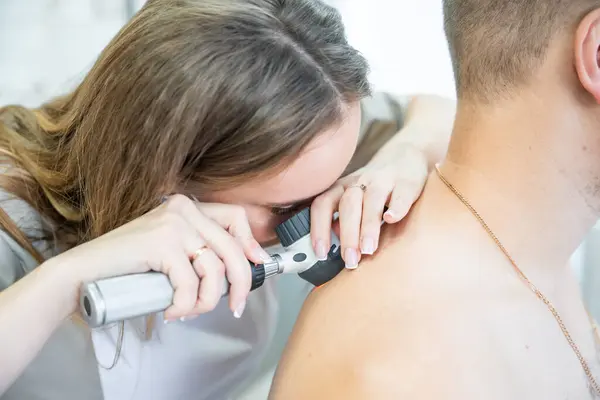 Doctor dermatologist examines skin and moles of patient. Dermatoscopy, prevention of melanoma, skin cancer concept. High quality photo