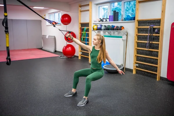 Training in the gym for the figure correction. Young woman doing fitness exercises at gym. High quality photo